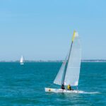 Two sailboats navigating on a clear blue sea under a bright sky, perfect for a sailing adventure.