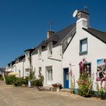 Quaint houses with flowers on a sunny day in a Breton village, perfect for travel and architecture themes.