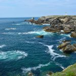 Stunning coastal cliffs and lighthouse at Pointe des Poulains, Bretagne under a clear blue sky.