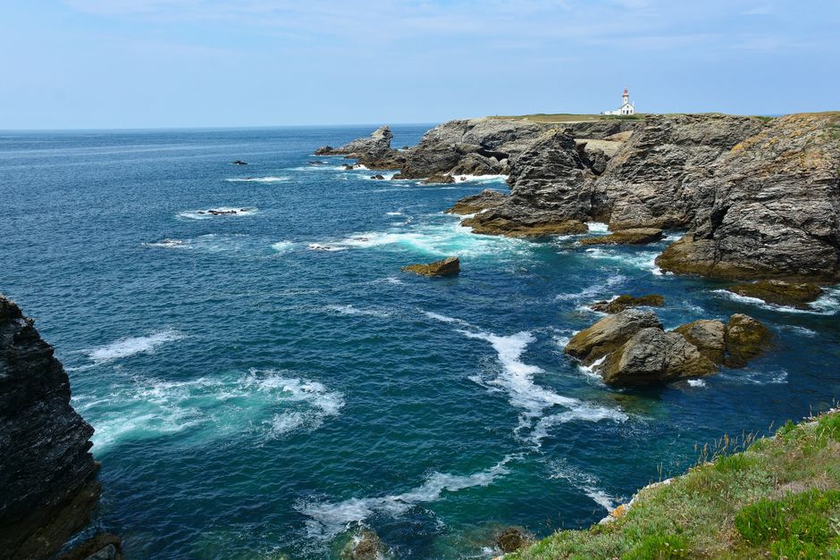 Stunning coastal cliffs and lighthouse at Pointe des Poulains, Bretagne under a clear blue sky.