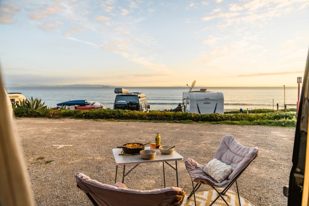 Campervans parked by the sea with outdoor dining setup