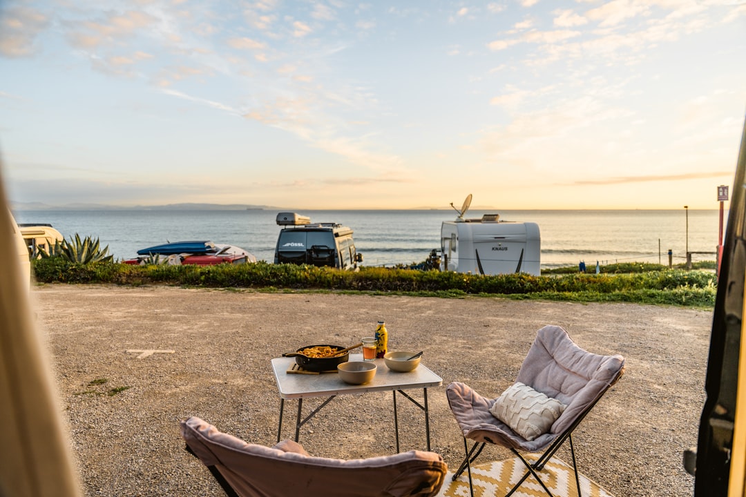 Campervans parked by the sea with outdoor dining setup