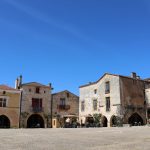 Picturesque medieval square with stone buildings under clear blue skies.