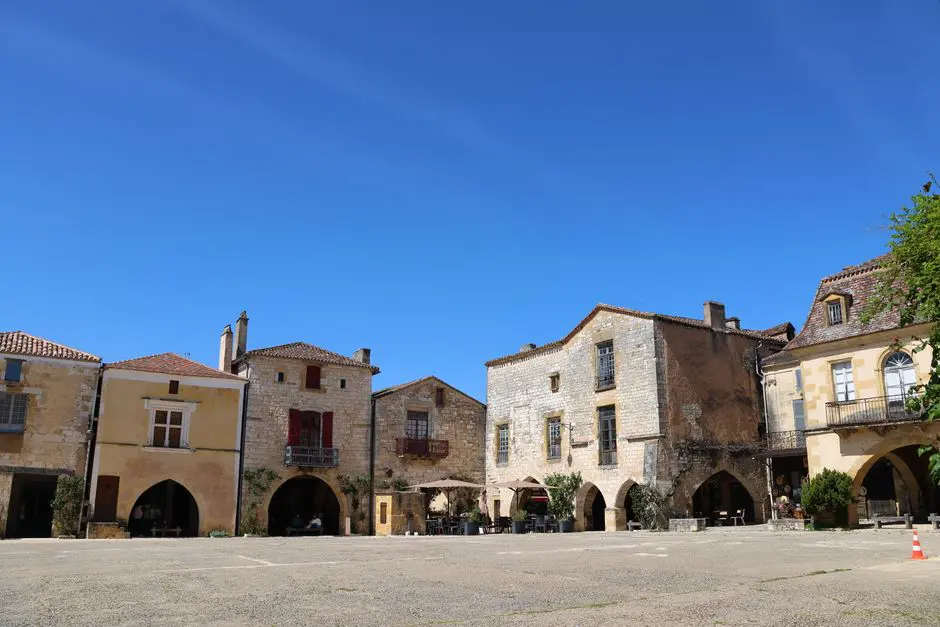 Picturesque medieval square with stone buildings under clear blue skies.